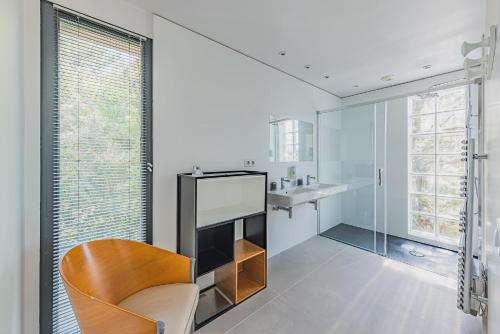 a white bathroom with a chair and a sink at Villa Ciel, vue mer in Pyla-sur-Mer