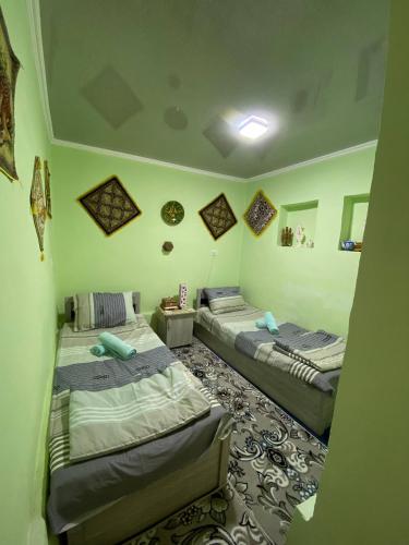 two beds in a room with green walls at Guest house Lovely Guest in Bukhara