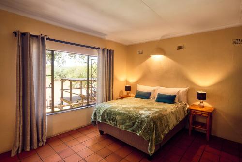 a bedroom with a bed and a large window at Parsons River Camp in Balule Game Reserve