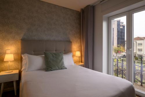 a bedroom with a large bed and a window at Terro Collection - Eça de Queirós in Braga