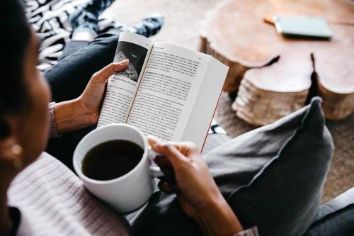 a person reading a book and a cup of coffee at Stunning Bush Beach House! NEW! in Elizabeth Beach