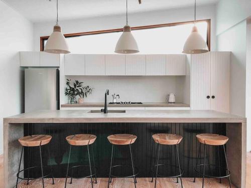 a kitchen with a counter with four stools at Stunning Bush Beach House! NEW! in Elizabeth Beach