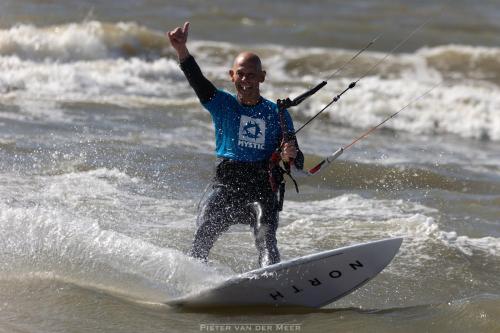 a man riding a wave on a surfboard in the ocean at Skip Inn Strandhuisjes in Katwijk aan Zee