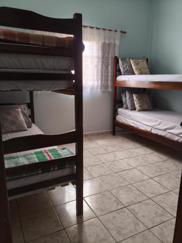 a room with two bunk beds and a tiled floor at Casa de praia in Peruíbe