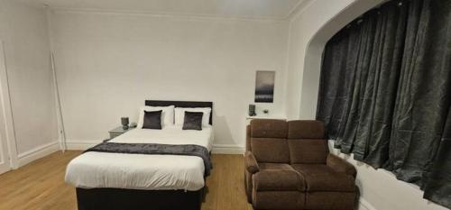 a bedroom with a bed and a chair at Spacious Two Bedroom Flat with Dedicated Workspace in Worsley in Worsley