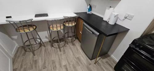 a kitchen with a counter and three bar stools at Spacious Two Bedroom Flat with Dedicated Workspace in Worsley in Worsley