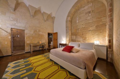 a bedroom with a bed and a stone wall at B&B Palazzo Personè Dimora Storica in Lecce