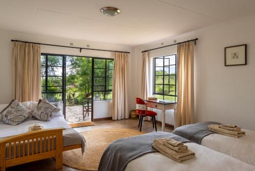 a bedroom with two beds and a desk and window at The Maa Guest House in Talek