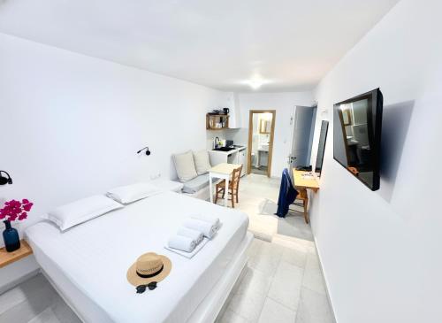 a white bedroom with a bed and a tv at Castellino Naxos in Naxos Chora