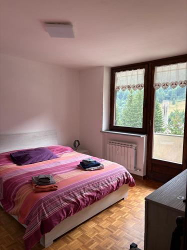 a bedroom with a bed and two windows at Appartamento G&G in Pontechianale