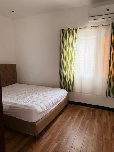 a small bedroom with a bed and a window at Casa Olivia in Puerto Galera