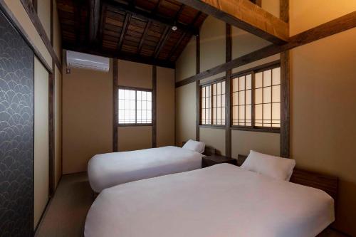 a bedroom with two beds and two windows at Choya Goshominami Machiya House in Kyoto