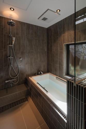 a bathroom with a bath tub and a shower at Choya Goshominami Machiya House in Kyoto