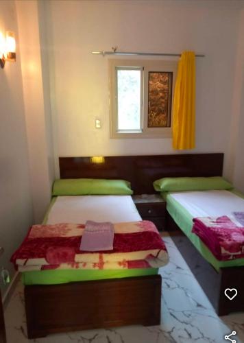 two beds in a small room with a window at Esmerada in Aswan