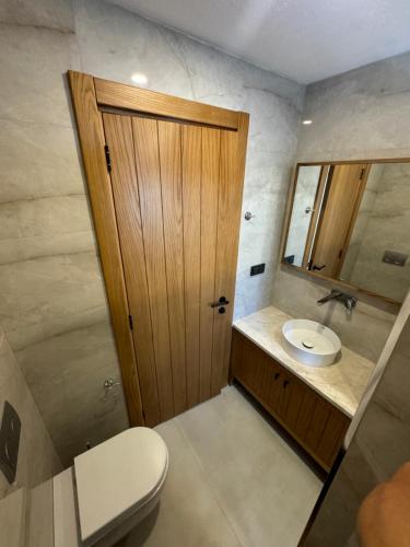 a bathroom with a toilet and a sink and a wooden door at Ultava Koru Suites in Datca