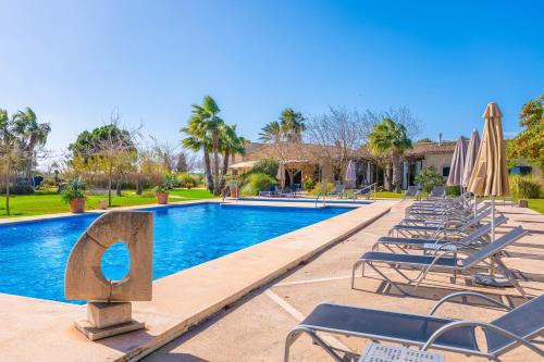 a pool with lounge chairs and umbrellas at a resort at Agroturismo Mondrago -Antic Na Martina- in Portopetro