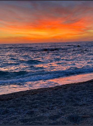 a sunset over the ocean with a sandy beach at Sun N Sand in Ligia