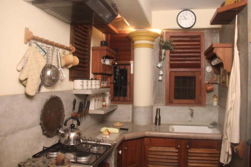 a kitchen with a stove and a clock on the wall at Vintekta Cottage in Weligama