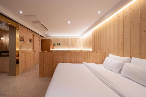 a bedroom with a large white bed and wooden walls at Dongdaemun Signature Tourist Hotel in Seoul