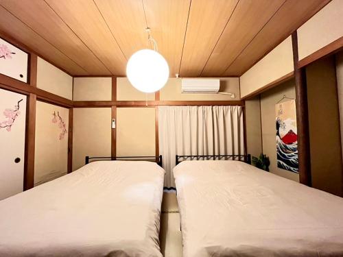 two beds in a small room with a ceiling at 8 people can stay in a house in Chikushino