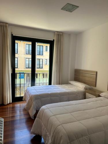a hotel room with two beds and a large window at Piso Ría de Ribadeo in Ribadeo
