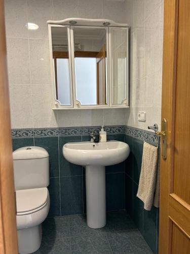 a bathroom with a sink and a toilet and a mirror at Piso Ría de Ribadeo in Ribadeo