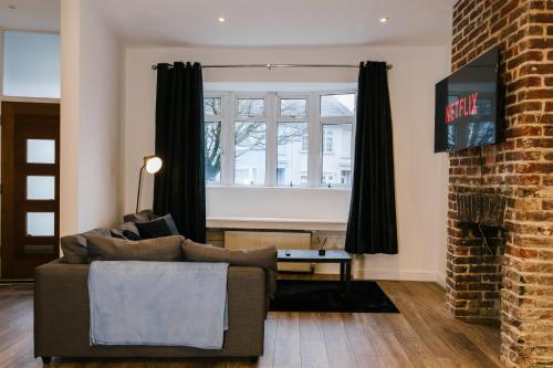 a living room with a couch and a brick fireplace at Charming Coastal Retreat in BN2 in Brighton & Hove