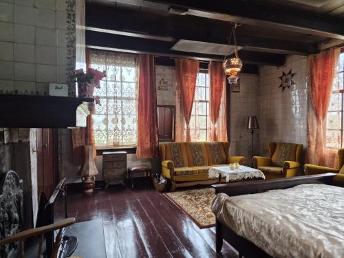 a room with a bed and a couch and windows at Bed and Breakfast Reestdal in Meppel