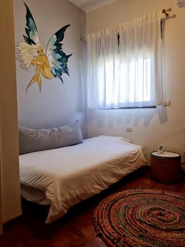 a bedroom with a bed with a angel on the wall at בין צבעי החול in Sappir