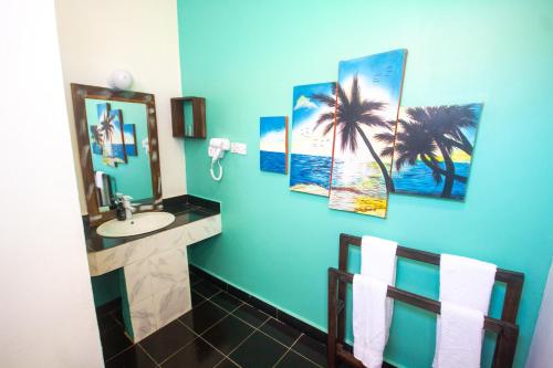 a bathroom with a sink and some pictures on the wall at Reef & Beach Resort - Spa Jambiani in Jambiani