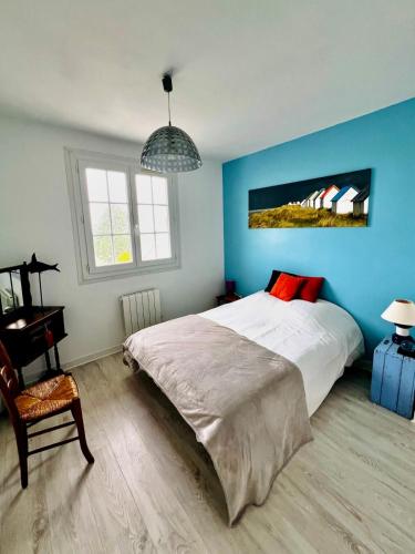 une chambre avec un lit et un mur bleu dans l'établissement Clopoing, à Barneville-Carteret
