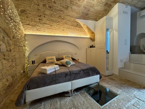 a bedroom with a bed and a stone wall at La Neviera Apulia Rooms in Altamura