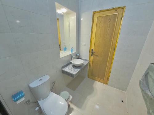 a bathroom with a toilet and a sink and a door at Talia gust house in Al Aqālitah