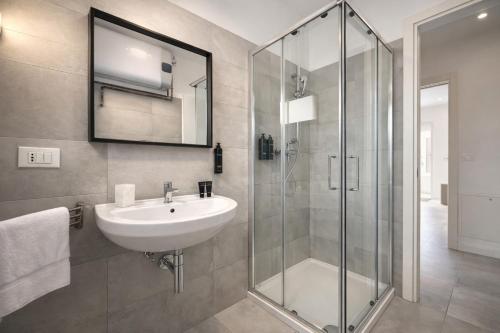 a bathroom with a sink and a glass shower at Villa Greif Apartment in Lignano Sabbiadoro