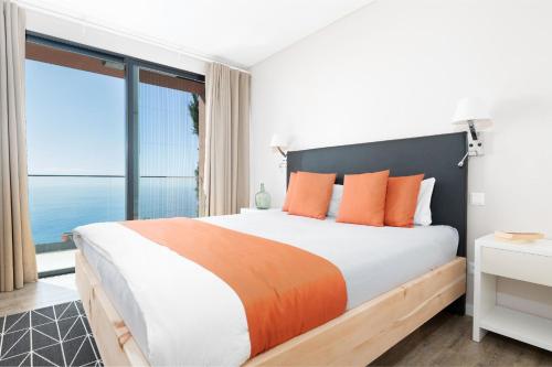 a bedroom with a large bed with orange pillows at Elísio do Mar by LovelyStay in Prazeres