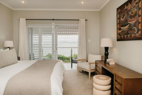 a bedroom with a bed and a desk and a window at House Olive in De Kelders
