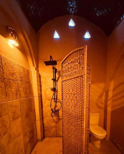 a bathroom with a toilet and a cross on the wall at Aghurmi Siwa Hotel in Siwa