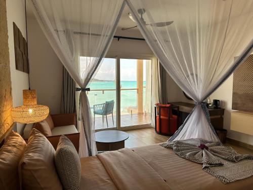 a bedroom with a bed with a view of the ocean at Reef & Beach Resort - Spa Jambiani in Jambiani