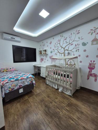 a bedroom with two beds and a crib and a tv at Casa 4 quartos com piscina em Aparecida de Goiania in Aparecida de Goiânia