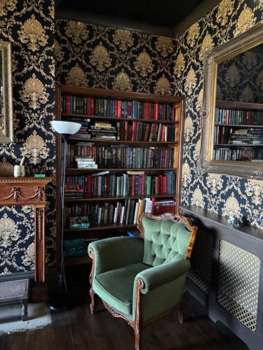 a room with a chair and a book shelf with books at Keats Green Hotel in Shanklin