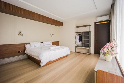 a bedroom with a bed with white sheets and wooden floors at Casa Miera in Bandung