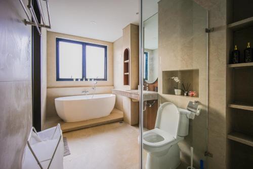 a bathroom with a tub and a toilet and a sink at Casa Miera in Bandung