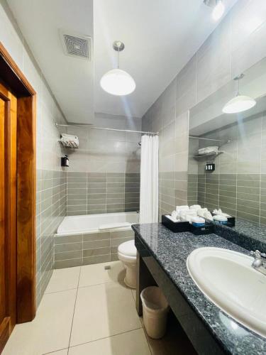 a bathroom with a sink and a toilet and a tub at Hotel Galerias HN in San Pedro Sula