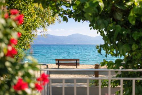 a bench sitting on the beach near the water at Moukas Seaside Apartments Romantico in Selianitika