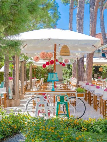 a patio with tables and chairs under a white umbrella at Hotel La Pineta Al Mare in Forte dei Marmi