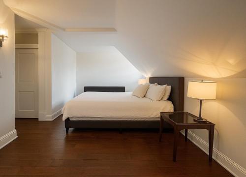 a bedroom with a bed and a table with a lamp at Hidden Gem Steps From River, Restos, Cafés, Parks in Windsor