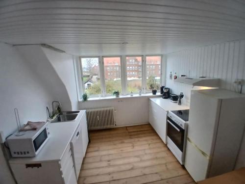 a kitchen with white counters and a white refrigerator at city apartment, next to the Beach in Fredericia