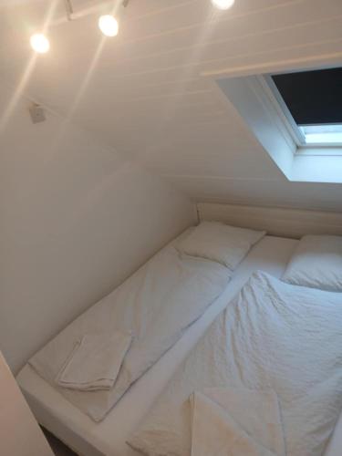 a white bed in a room with a window at city apartment, next to the Beach in Fredericia