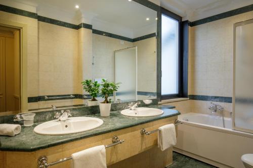 a bathroom with two sinks and a tub and a mirror at Donna Laura Palace by OMNIA hotels in Rome