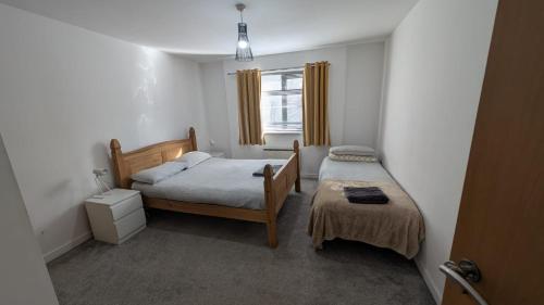 a small bedroom with two beds and a window at 2 Bedroom 2 Bath Apartment, sleeps 4, Town Centre in Wolverhampton